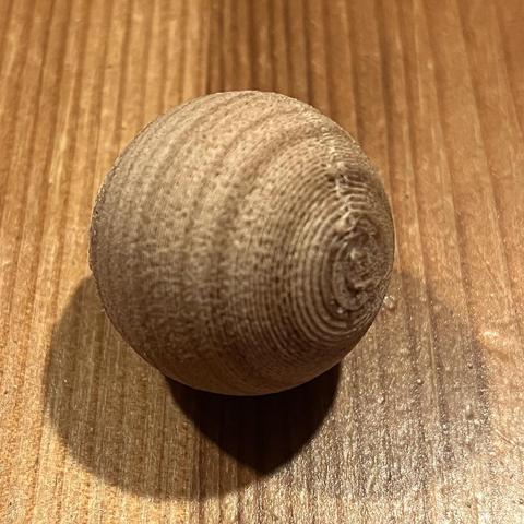 Closeup of a 25mm sphere 3d printed out of LAYWOO-D3 Wood Filament with some postprocessing script applied to produce a wood grain texture.