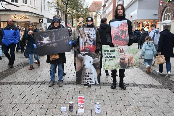 Aktivis stehen in der Innenstadt und halten Schilder mit Tieren darauf und Sprüchen wie "Kein Lammbraten" die Stadt ist sehr voll.