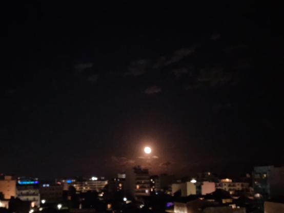 Luna al suo sorgere da dietro i palazzi, in un cielo stellato e sereno