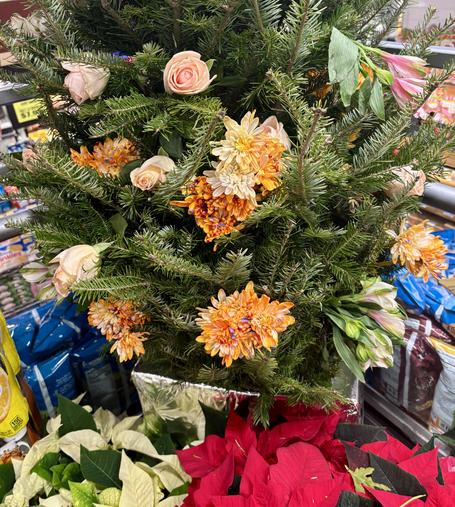 Yule tree inside, decorated with fresh cut flowers. Red and white poinsettias below.