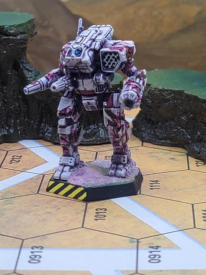 An Orion battlemech, seen from the front right quarter.  Its base sides are painted flat black, with yellow hazard striping on the business end, and the base top is grass green covered with pink flocking standing in for fallen cherry and plum blossoms, while a dirt path runs from the rear right hex side, across the base, under the left foot, and out through the rear left hex side.

The overall paint scheme is white with warm magenta shadows, with all four limbs, the right torso, and the left shoulder all covered with tree branches bearing many cherry and plum blossoms, which the left shoulder, over the branches, holds the black circle, filled with red, with a snarling asian dragon, the logo of the Draconis Combine.

The mech's twin cockpit windows have been jeweled with blue, black, and white, and the way the windows are arranged makes them look a bit like absurd anime eyes.