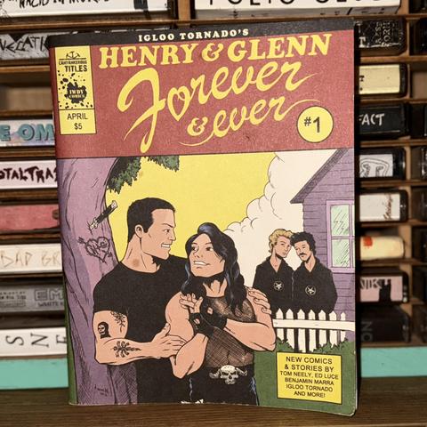 The image features a comic book titled "Henry & Glenn Forever & Ever #1," showcasing a colorful cover illustration. It depicts two muscular men in a playfully romantic pose, surrounded by whimsical elements, while two others watch from a nearby house.