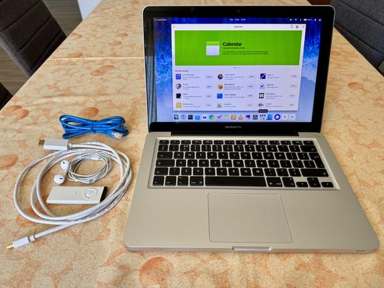 A mid-2012 13” MacBook Pro booted into elementary OS 8, sitting on a table beside several media accessories. Only Broadcom WiFi drivers needed installation via ethernet; even the old Apple Remote worked without configuration (as a HID device). Finally, a way to steam audio CDs to the HomePod mini—after configuring PipeWire to add AirPlay 2 functionality