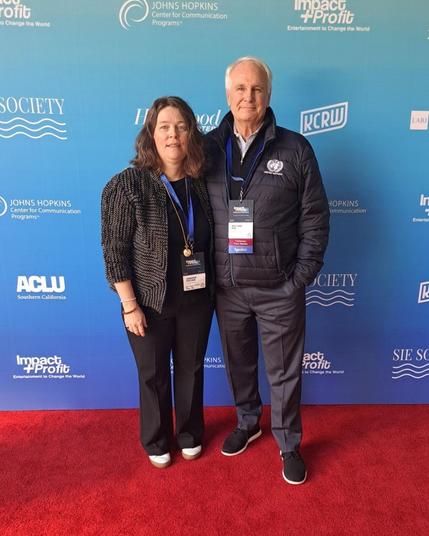 Journeys in Film Executive Director Jennifer Fisher and SIE Society Founder and Co-Executive Director pose together for a photo against the branded conference backdrop at the SIE Society's Impact + Profit 25 conference.