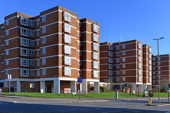 Photo of a group of three residential blocks, brick clad, raised on concrete piers. Providing 107 retirement flats. A proposal to add another 5 storeys to each of the towers has been made by BakerBrown studio. City of Brighton & Hove, UK.