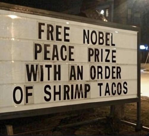FREE NOBEL
PEACE PRIZE
WITH AN ORDER
OF SHRIMP TACOS
sign made up with individual letters black on a white sign that presumably lights up at night