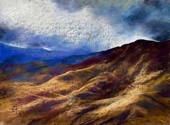 Looking down on a mountain that is lit by the light that falls through rain clouds.