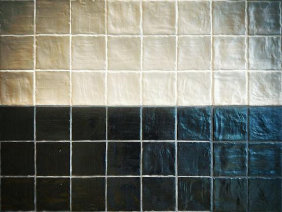 White tiles fill the top half of the frame, with black tiles filling the bottom half.