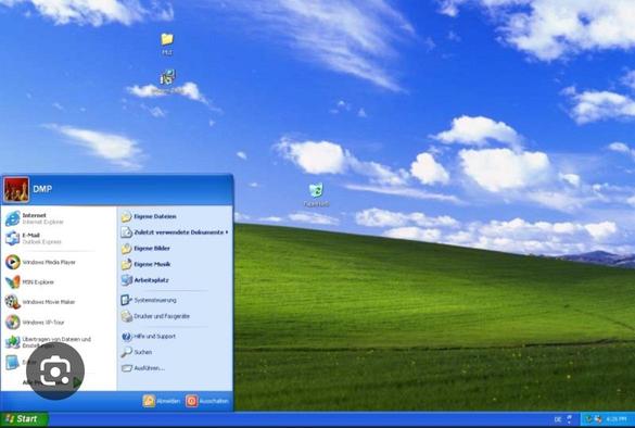 Screenshot eines klassischen Windows XP Desktops mit einem blauen Himmel und einem grünen Gras-Hintergrundbild. Das Startmenü ist geöffnet und zeigt verschiedene Anwendungen und Ordner.