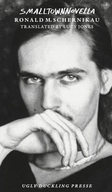 Cover of "Smalltown Novella" by Ronald Schernikau; The pic on the cover is a black and white photograph of the author, a stylish looking young man with a sharp face, neat eyebrows, a thin moustache, long hair. He holds his slender hand elegantly in front of his mouth and looks directly at the camera with intense, expressive eyes.