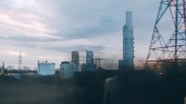 industrial site in grey haze light, pylon cropped foreground, all from a speeding train