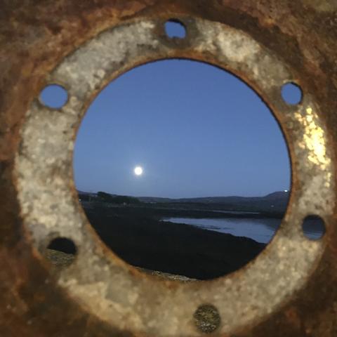 Vollmond bei Nacht, fotografiert durch rundes rostiges Eisenteil.