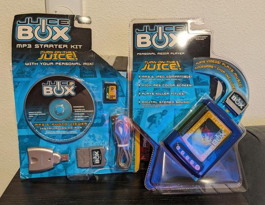 A picture showing the Mattel Juice Box still in package alongside an MP3 starter kit for the same media player.