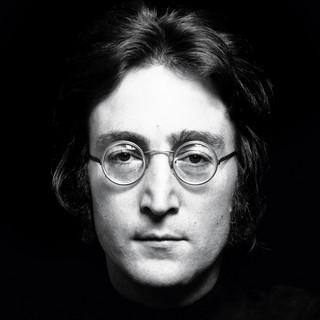 A black and white closeup photo of John Lennon's bespectacled face.