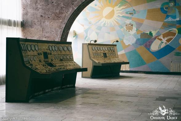 Two retro control panels stand against an artistic wall wiht mural