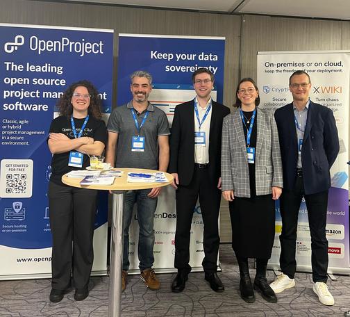 Group photo at the OpenProject booth during OSXP 2025 featuring Pauline Bessoles, Christophe Bliard, Robin Wagner, Kristin Lüdecke, and Dan Jayes.
