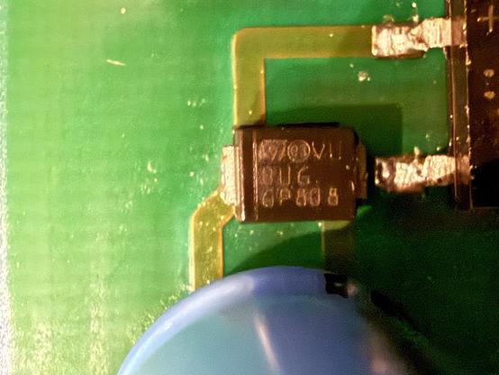 Close-up image of a printed circuit board (PCB) featuring a semiconductor component, with visible markings and connections. The background is a green textured surface.