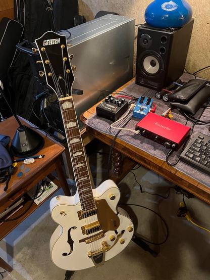 White Gretsch 5422 hollow body guitar on stand in basement.