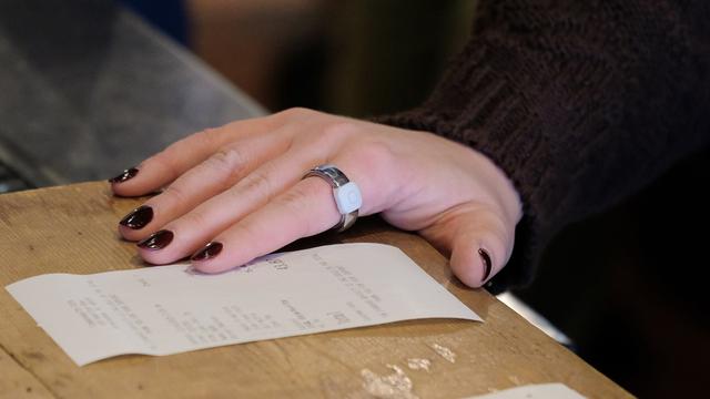 <figure class="wp-block-image size-large"><img alt="" class="wp-image-870523" height="596" src="https://files.tecnoblog.net/wp-content/uploads/2025/12/pebble-ring-1060x596.jpeg" width="1060" /><figcaption class="wp-element-caption">Novo Index 01 foca em gravações de voz (imagem: reprodução/Pebble)</figcaption></figure>
<details class="tb-resumo tb-callout padrao">
Resumo
<div class="tb-resumo-topicos tb-callout-texto"><ul>
<li>O Pebble Index 01 é um anel inteligente focado em anotações de voz, custando US$ 75, com lançamento previsto para março de 2026.</li>
<li>O dispositivo opera via Bluetooth com um app dedicado, transcreve áudio capturado e possui armazenamento local para cinco minutos de gravação.</li>
<li>O Index 01 é de código aberto, permitindo desenvolvimentos futuros, e oferece integração com apps como Notion e potencial para uso com inteligência artificial.</li>
</ul>
</div>
</details>
<p>Após a onda de anéis inteligentes para monitoramento de saúde, agora o empresário conhecido pela marca de smartwatches Pebble aposta num anel que dispensa sensores fitness e traz um microfone acessível pelo dedo.</p>
<p>Ao contrário do <a href="https://tecnoblog.net/noticias/galaxy-ring-samsung-revela-detalhes-do-primeiro-anel-smart-do-brasil/">Galaxy Ring</a> e outros produtos similares, o dispositivo Index 01 possui apenas um botão físico e um microfone. Ao pressionar o botão com o polegar, o usuário pode ditar notas, lembretes, listas de tarefas ou configurar ala