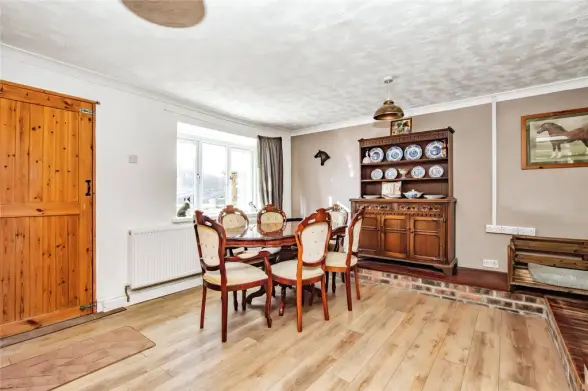Wooden dining table with ornate chairs and plate display hutch in a rustic dining room.