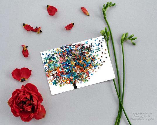 Colorful tree on white displayed as a greeting card surrounded by red flower and petals.  Art by Sharon Cummings.