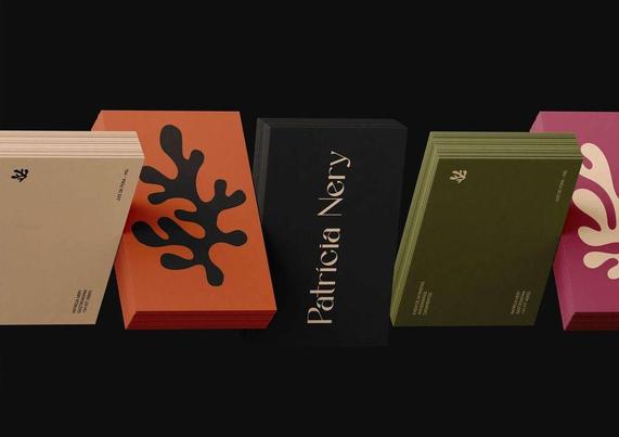 A collection of stylish business cards in various colors with organic designs, prominently featuring "Patrícia Nery" on a black card.