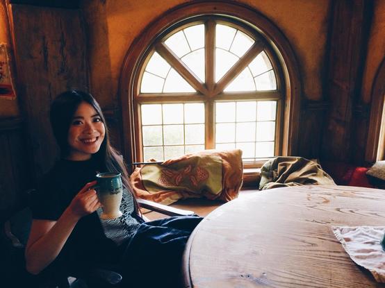 2014 photo of Chicago artist Jenny Lam drinking Southfarthing ale in the Green Dragon in Hobbiton movie set, Matamata, New Zealand