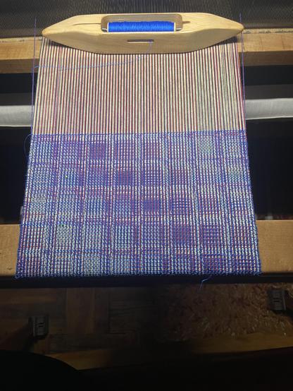 Weaving in progress on the loom. The pattern is rows of boxes but the colors go diagonally and blend into one another.