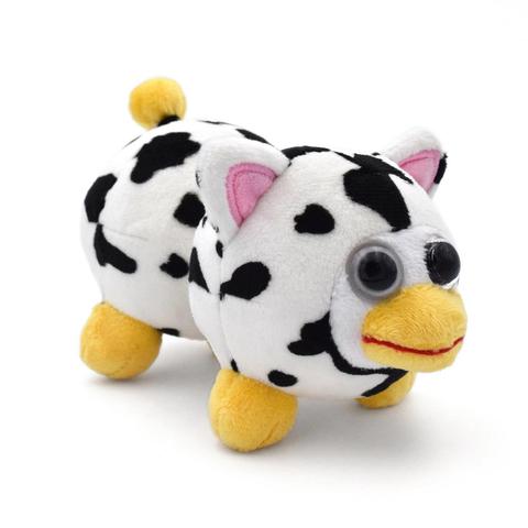 A peanut-shaped stuffed animal with cow patterns all over its twin spheres. It has stubby yellow legs, a bobble-shaped yellow tail, and pink cat-like ears. It has a white circular face, on which are two bulging eyes and a yellow beak separated by a red horizontal line. The creature is both cute and disturbing.