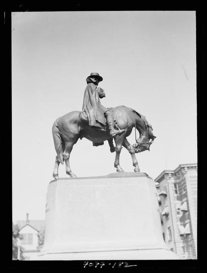 The image depicts a black and white photograph of an equestrian statue, featuring a figure in riding attire atop a horse. The rider appears to be dressed as if from the 19th century or earlier, with wide-brimmed hat and cloak-like garment that covers most of their body. They are seated on a large pedestal which supports both themselves and the horse. Behind them is an urban background including buildings typical of what might have been found in cities during early to mid-20th-century America.

There's text at the bottom right corner indicating "Photographed by" followed by a series of numbers: 7914/82, suggesting this may be part of a collection or catalog. Another piece of information reads 'Equestrian statues Washington D.C. between', which likely refers to the era these types of monuments were prominent.

This photograph is an actual physical print and not a digital file; it shows signs consistent with aged photographic materials such as dust spots, slight fading around edges due to creasing or handling over time. The photo seems relatively well-preserved but bears marks indicative of its age and use in archival work or similar environments where items are handled frequently.

The photograph is credited to Arnold Genthe (1869-1942), a renowned photographer who documented various aspects of life, including cultural events and urban landscapes during his career spanning  [...]