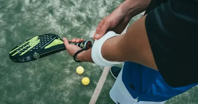 A person holds a padel racket and is photographed from above. This image is being used to represent the inclusion of people with disabilities in sport.
