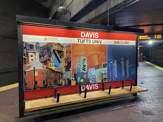 A bench at the Davis Square T stop in Somerville MA in 2022. The bench is finished wood.