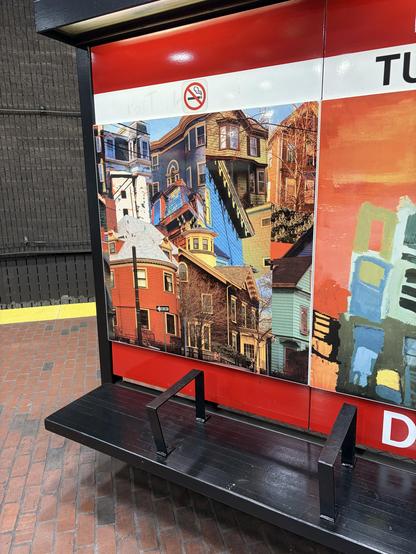 A bench at the Davis Square T stop in Somerville MA in 2025. The bench is wooden but painted black.