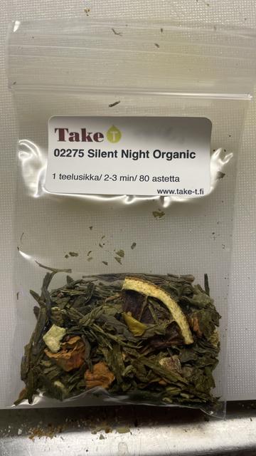 A small ziplock bag with tea leaves in it. The label on top states the names of the tea shop and the tea blend. Inside the bag some fruit pieces and rind is visible amongst the tea leaves.