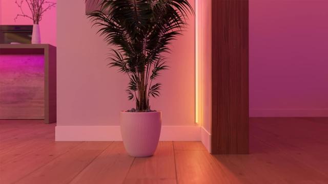 Philips Hue Leuchtstreifen ist in einer Zimmerecke angebracht worden und leuchtet gelb-orange. Foto (c) Philips.