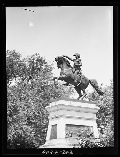 The image depicts a black and white photograph of an equestrian statue, with the central figure on horseback. The rider is depicted in mid-action atop a rearing horse that stands upon a tall pedestal base. This suggests it's likely to be commemorating someone of historical significance or importance due to its grandiose nature.
The image includes several elements indicating context and possibly location details such as "70 3" at the bottom which might refer to an archive, photograph number, or date code; additional text on a plaque is present but not legible in this description. The background shows dense foliage indicative of trees or shrubbery commonly found within parklands.
The photographer's name appears to be Genthe Arnold (1869-1942), with the format "Genthe, Arnold, 1869-1942" visible as a caption below his work. The reference suggests that this photograph is part of a collection or exhibit about equestrian statues in Washington D.C., spanning from approximately early 1900s to mid-century.
The photographic negative format and style hint at historical significance, potentially dating back over a century. This visual piece serves as both an artistic expression commemorating notable figures through sculpture while documenting the cultural heritage of America's capital city during that time period.