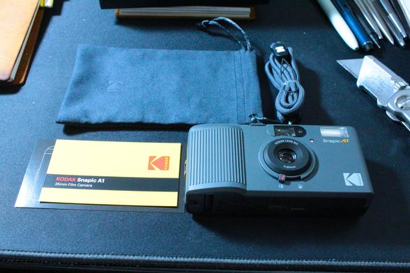 Here are the camera and it's accessories taht came with it.  You get the camera it's self, a small black fabric pouch with draw string closure to put the camera in when not in use.  A gray rope lanyard long enough to hang the camera around your neck, and a couple small cards that have some basic instructions and QR codes for the quick start guide on the back.