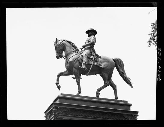 This black and white photograph depicts a large equestrian statue of a figure, likely historical or military significance, atop a horse. The rider is dressed in what appears to be 19th-century military uniform with a hat that has an emblem on the front side. The pose suggests movement, as if captured mid-trot, which adds dynamism and life-like quality to the statue. Below this equestrian figure stands a rectangular pedestal adorned with ornate designs at its corners. To the right of the frame is part of a tree or bushy plant against an overcast sky background, providing contrast in texture.

The photograph itself has white margins suggesting it may have been cut from a larger sheet of photographic paper, typical for albumen silver print photographs which were popular during the late 19th and early 20th centuries. The image is titled "Equestrian statues Washington D.C." indicating that this statue could be located in or associated with Washington, DC.

There's no explicit context provided about where exactly within Washington it might be placed; however, based on historical knowledge of such monuments during the period mentioned (1911-1942), these equestrian statues were often erected to commemorate military leaders and figures significant to American history. Without more specific information or a view that includes surrounding elements for scale reference, precise identi [...]