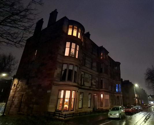 A street in Glasgow lined with sandstone tenements as seen at night.