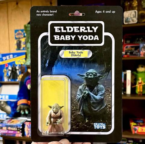 The Star Wars character Yoda as a toy figure in transparent packaging. The name of the fictional product is written in large letters at the top: “Elderly Baby Yoda.”