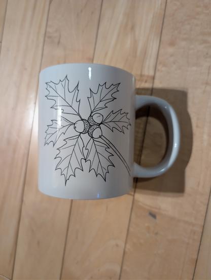 A white mug with a line drawing of acorns and oak leaves of the species quercus rubra - red oak. The mug is very large - 20 oz.