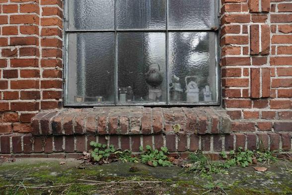 Fenster mit Metallrahmen und Sprossen in einer Ziegelwand. Digitale Farbaufnahme.