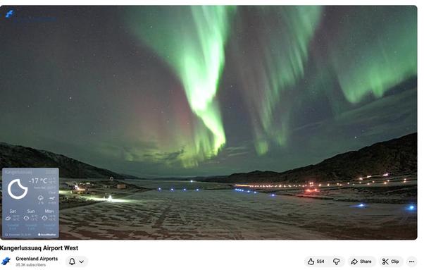 Bright green ribbons of light in the sky over a darkened air field smattered with snow