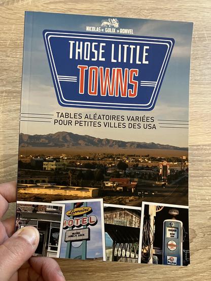 Couverture du livret de Those Little Towns, créé par Nicolas «&nbsp;Gulix&nbsp;» Ronvel.
Sous-titre : Tables aléatoires variées pour petites villes des USA
Quelques photos génériques, notamment façon Polaroïd, habillent la couverture.