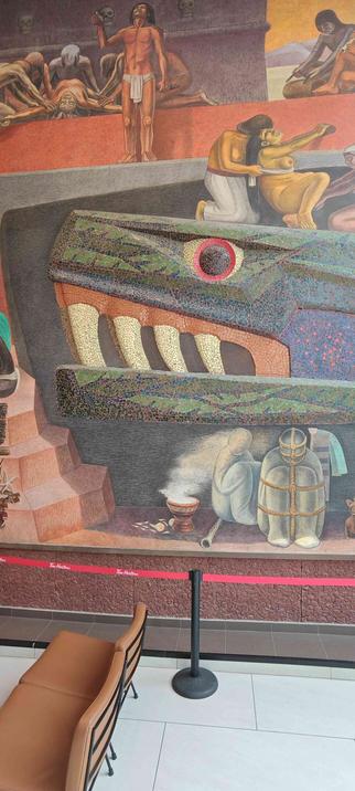 La cabeza de Quetzalcoatl sostiene a una mujer a punto de parir en un mural de José Chávez Morado. Debajo, una escena de enterramiento.