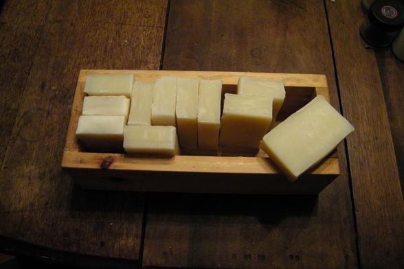 Bars of golden-cream colored soap in a wooden box on a table.