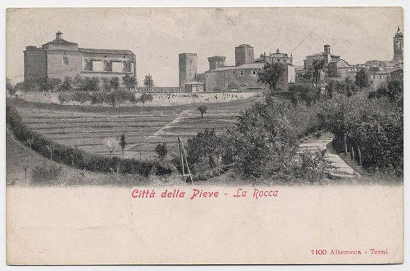 The image is a sepia-toned photograph depicting an urban landscape. Prominent in the scene are several buildings with varying architectural styles, including what appears to be historical and religious structures, as indicated by their domes and towers. A prominent feature within this setting seems to be a fortified structure or castle known as "La Rocca," which is noted on the image itself alongside Italian text translating from "City of Pieve - The Rock." This suggests that the location captured in the photograph could represent Città della Pieve, an area referred to by its historic fortress. Notably, there's a date at the bottom right corner indicating this photo may be historical: "1400 Alterocca," which might refer to an event or period associated with Terni, Italy. The overall scene conveys a sense of antiquity and possibly ties into local history related to Città della Pieve.