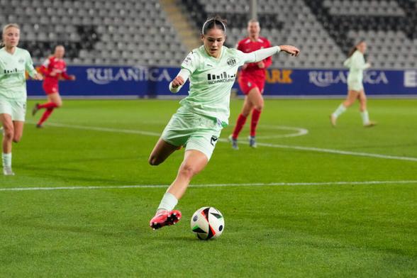 Kassandra Potsi im SGS Essen Trikot holt mit ihrem rechten Bein zum Schuss aus, dabei ist ihr linker Arm zur Seite gestreckt. Ihr Blick ist nach unten auf den Ball an ihren Füßen gerichtet.