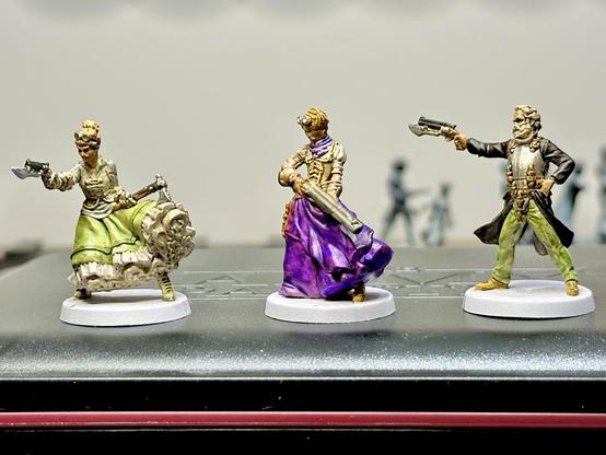 Photo of three small painted miniatures from the game Zombicide, with a steampunk western theme.