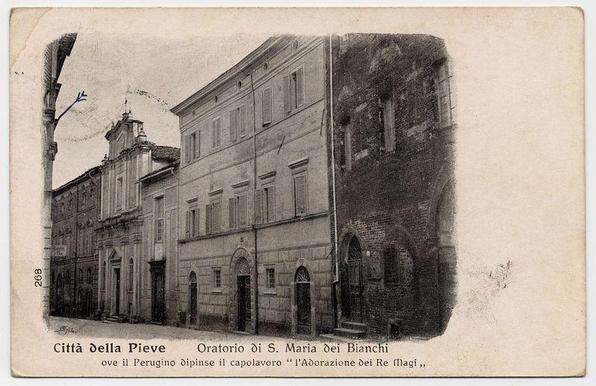 This image depicts a historical black and white postcard featuring the Oratorio di S. Maria dei Bianchi, also known as "L'Adorazione dei Magi" by Perugino, located in Città della Pieve. The photograph captures an old building with classical architectural features such as shuttered windows, arched doorways, and a distinctive dome-topped structure visible above the roofline of adjacent buildings.

The text on the postcard reads "Città della Pieve - Oratorio di S. Maria dei Bianchi" at the top in large font, followed by smaller text stating "ove il Perugino dipintse il capolavoro 'l'Adorazione dei Magi,'". The numbers 268 appear on the bottom left corner of the card.

The condition of the postcard shows signs of wear and age with creases along its edges, suggesting it is an old piece. There's a notable blue mark near the top right quadrant that could be either intentional or accidental marking from handling over time.

This image likely holds significance for those interested in art history, architecture, or the cultural heritage of Città della Pieve and Perugino’s work on this particular scene depicted by "L'Adoration dei Magi."